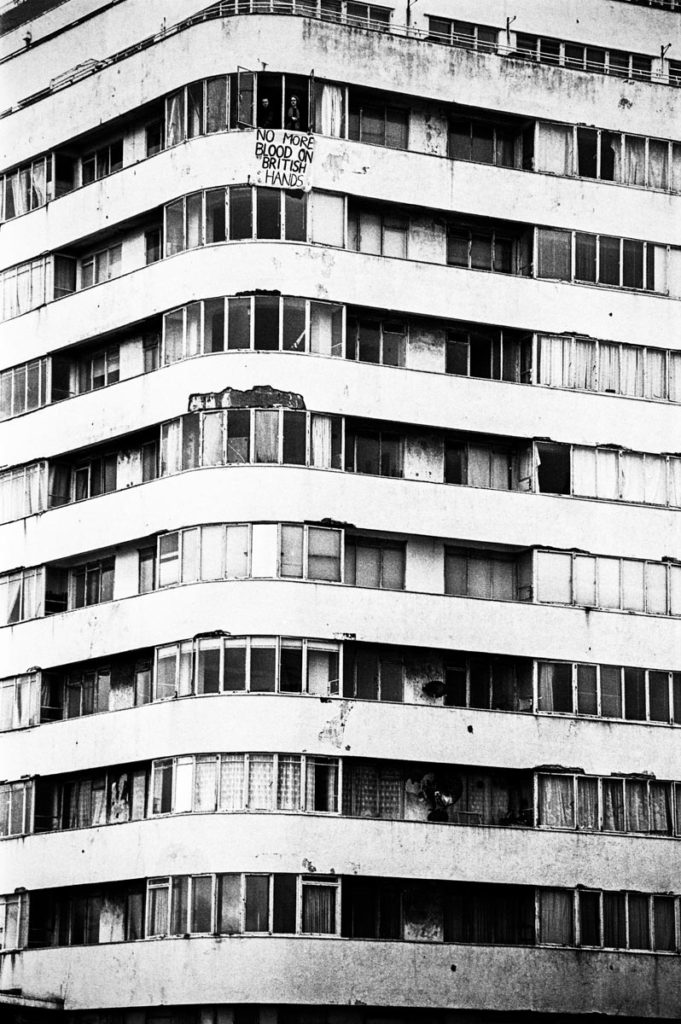A banner that reads, ‘NO MORE BLOOD ON BRITISH HANDS’ hangs from a window of Embassy Court in Brighton, England (2003). Image © Thaddeus Pope
