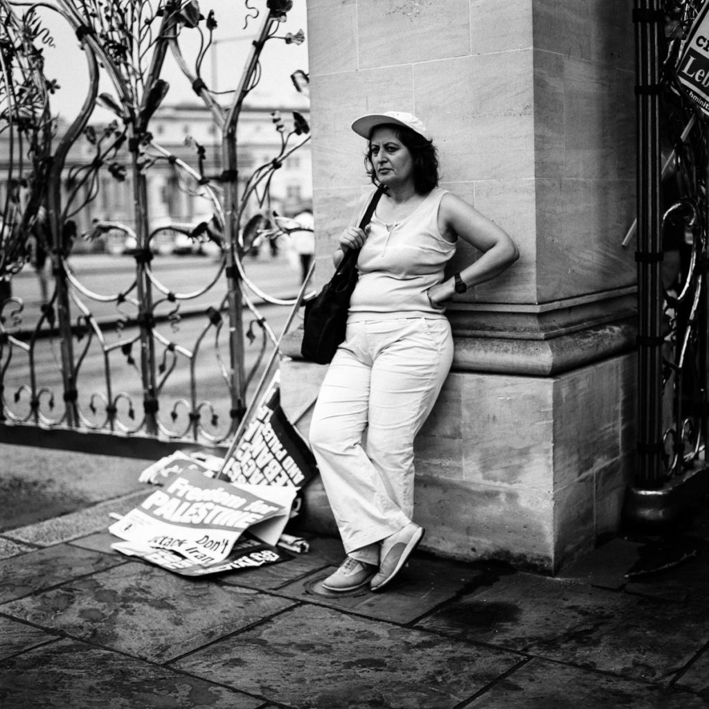 Following a day of action in central London which called on the UK government to help de-escalate the violent 33-day conflict between Lebanon and Israel known as the 2006 Lebanon War, an anti-war demonstrator rests against Hyde Park Gate next to a pile of discarded placards. Image copyright © Thaddeus Pope, 2006.
