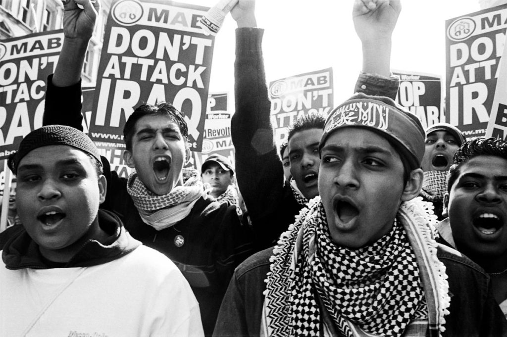 A group of young British Muslim men march down Whitehall during a peaceful anti-war protest in London, England (2003). Image © Thaddeus Pope