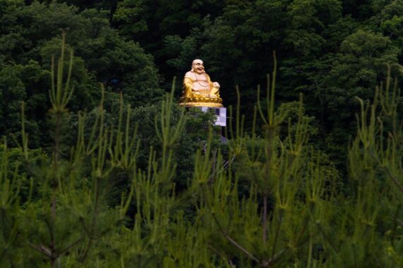 A large golden statue of Hotei sits on a hillside near Sanda in Hyogo Prefecture, Japan. Hotei is the God of fortune, guardian of the children, patron of diviners and barmen, and the god of popularity. Hotei is one of the Seven Lucky Gods that the Japanese began to believe in during the Edo era. A large golden statue of Hotei sits on a hillside near Sanda in Hyogo Prefecture, Japan. Hotei is the God of fortune, guardian of the children, patron of diviners and barmen, and the god of popularity. Hotei is one of the Seven Lucky Gods that the Japanese began to believe in during the Edo era.
