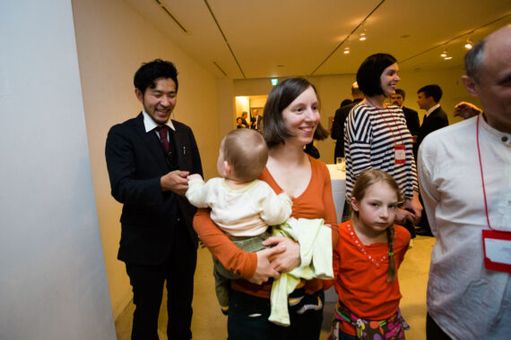 The maître d' of the conference welcome reception venue greets a group of delegates – including one professor carrying a very cute baby. The maître d' of the conference welcome reception venue greets a group of delegates – including one professor carrying a very cute baby.