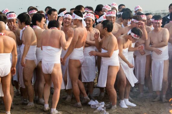The men huddle together and smoke cigarettes after the ritual purification ritual of misogi.