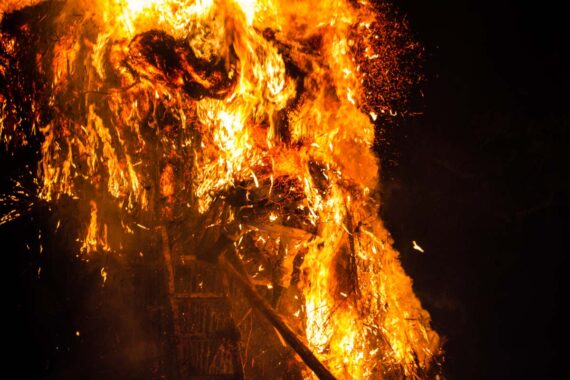 As a large portion of the suzumi collapses, a wall of flames and smoke surrounds one man.