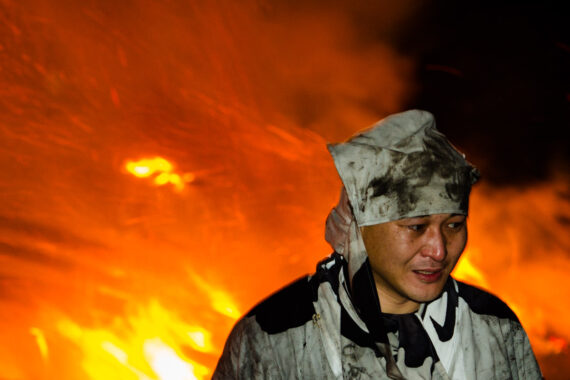 The men remove their masks to reveal faces fatigued by the immense physical effort of the task.